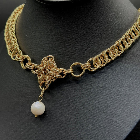 Gold chain necklace with a pearl pendant on a black mannequin head.