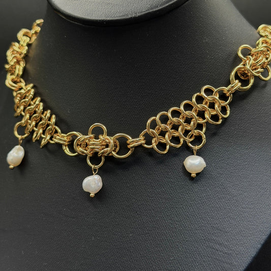 Gold chain necklace with pearl drops on a black stand
