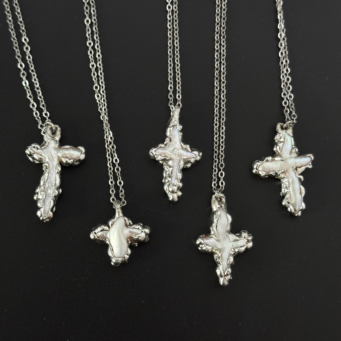 closeup of handmade gothic freshwater pearl cross necklaces molten metal design