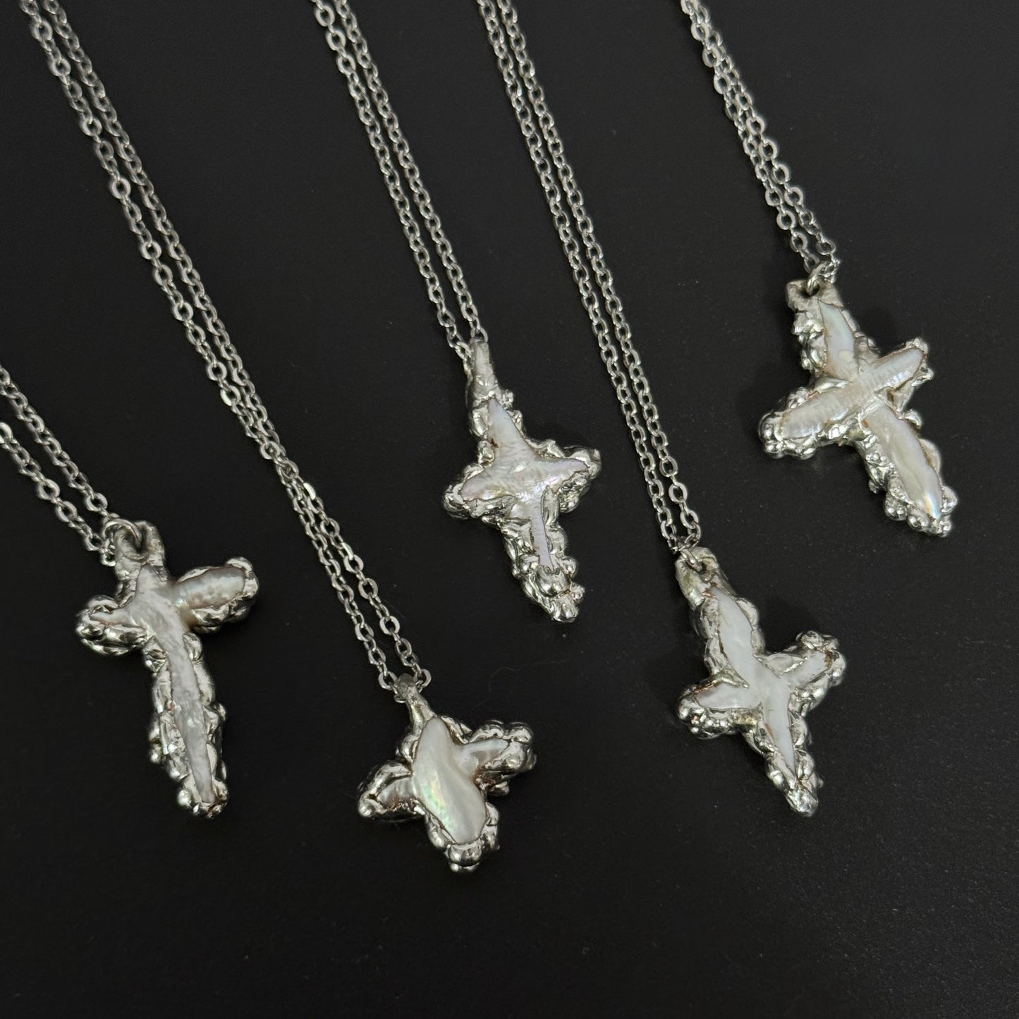closeup of handmade gothic freshwater pearl cross necklaces molten metal design