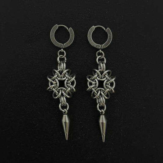 Pair of silver hoop earrings with star-shaped pendants and spike details on a black background