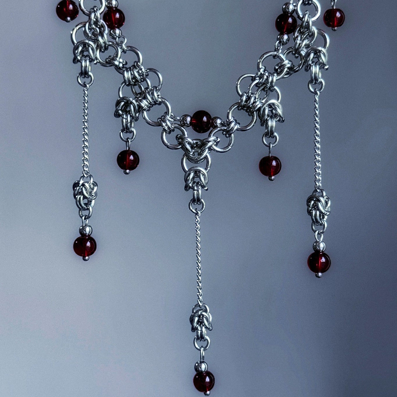 Silver chain necklace with red beads on a gray background