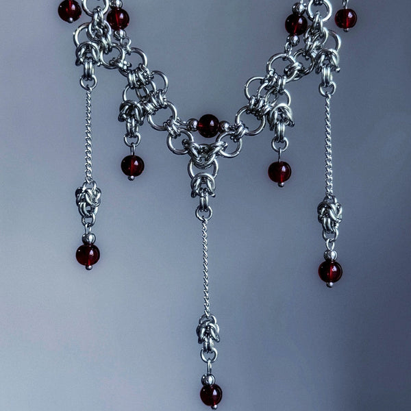 Silver chain necklace with red beads on a gray background