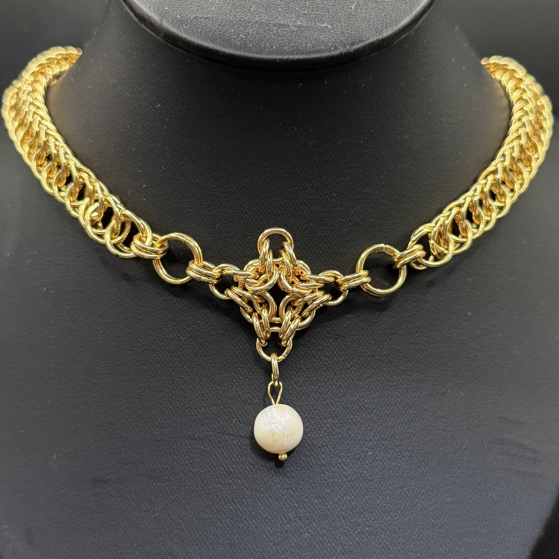 Gold chain necklace with a pearl pendant on a black background