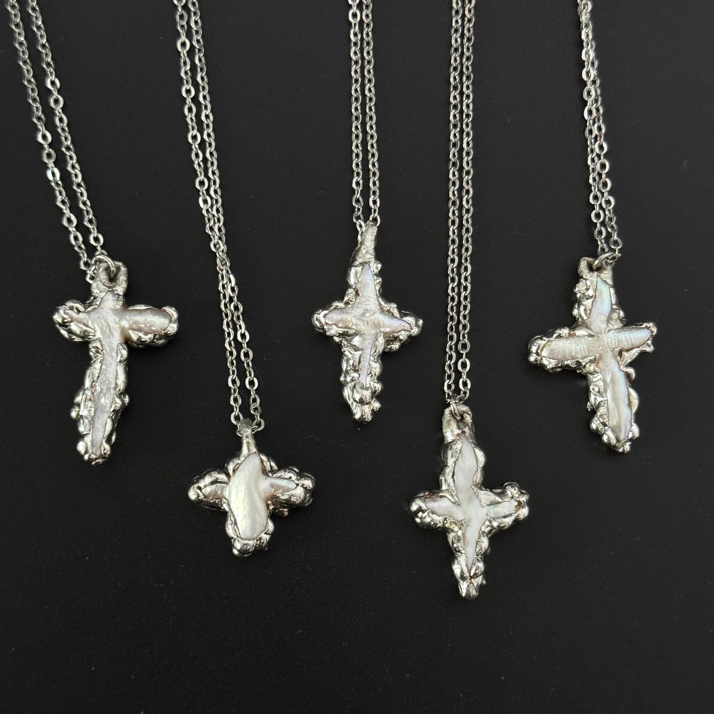 closeup of handmade gothic freshwater pearl cross necklaces molten metal design 