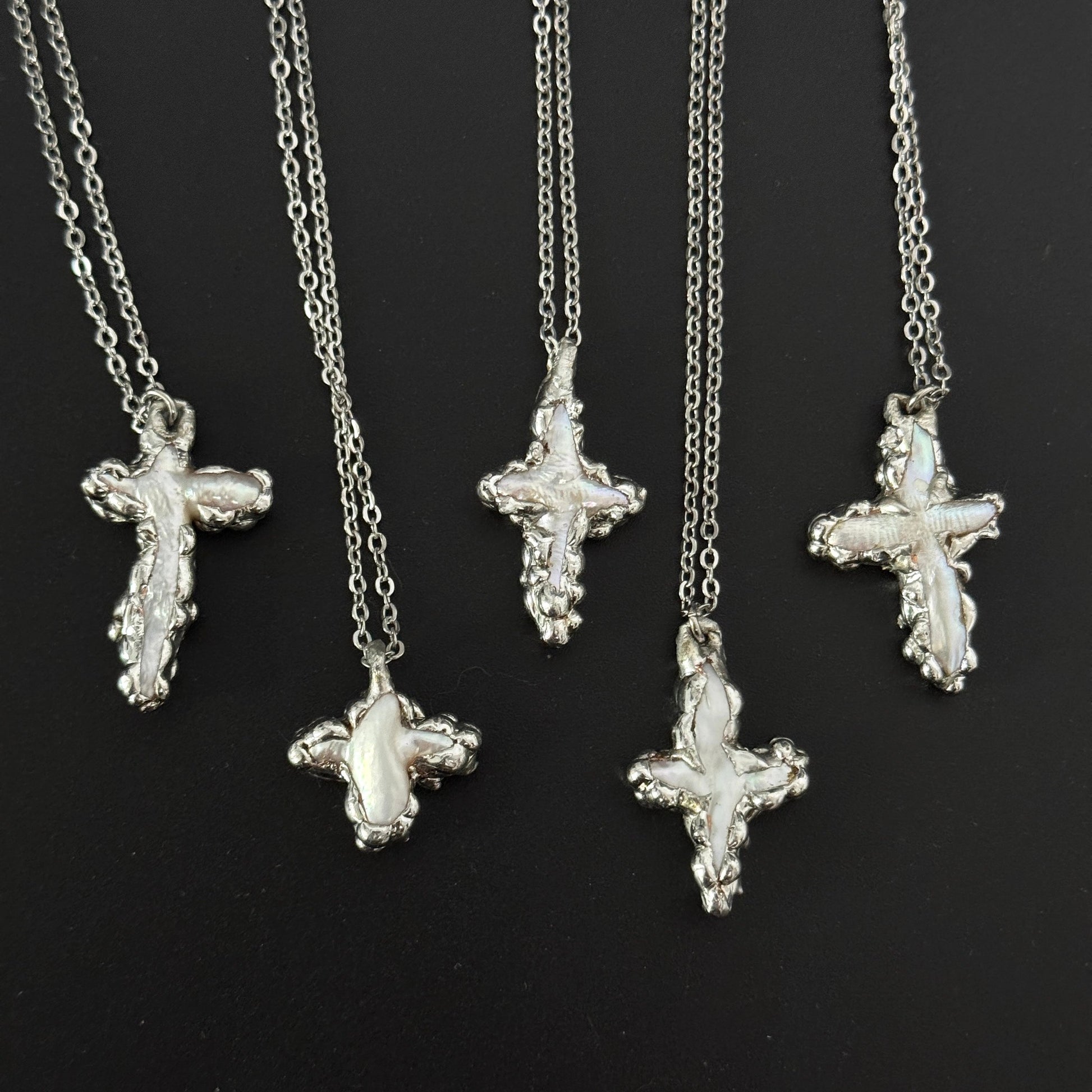 closeup of handmade gothic freshwater pearl cross necklaces molten metal design 