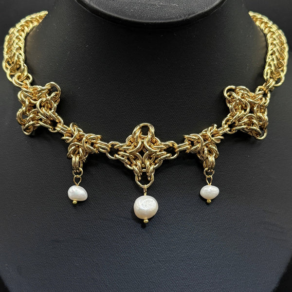Gold chain necklace with pearl pendants on a black background