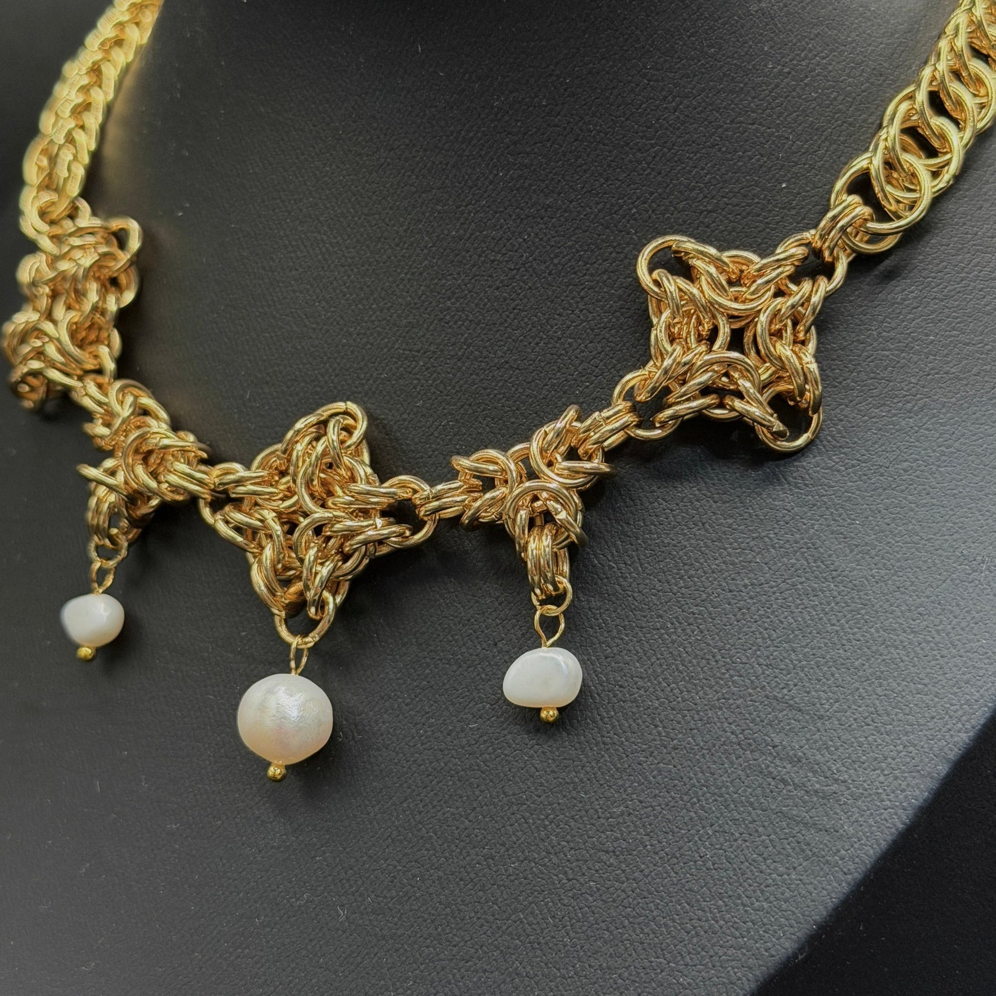 Gold necklace with pearl drops on a black background